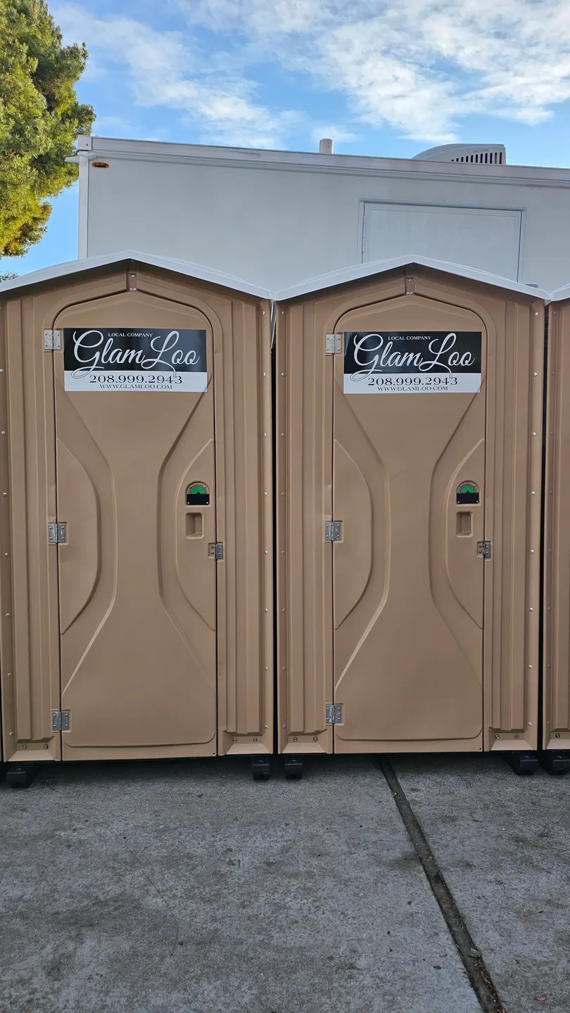 A row of portable toilets with the doors open.